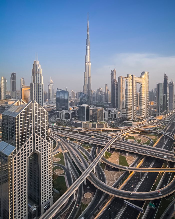 Stunning aerial shot of Burj Khalifa and Dubai's modern skyline with intricate road network at sunset.